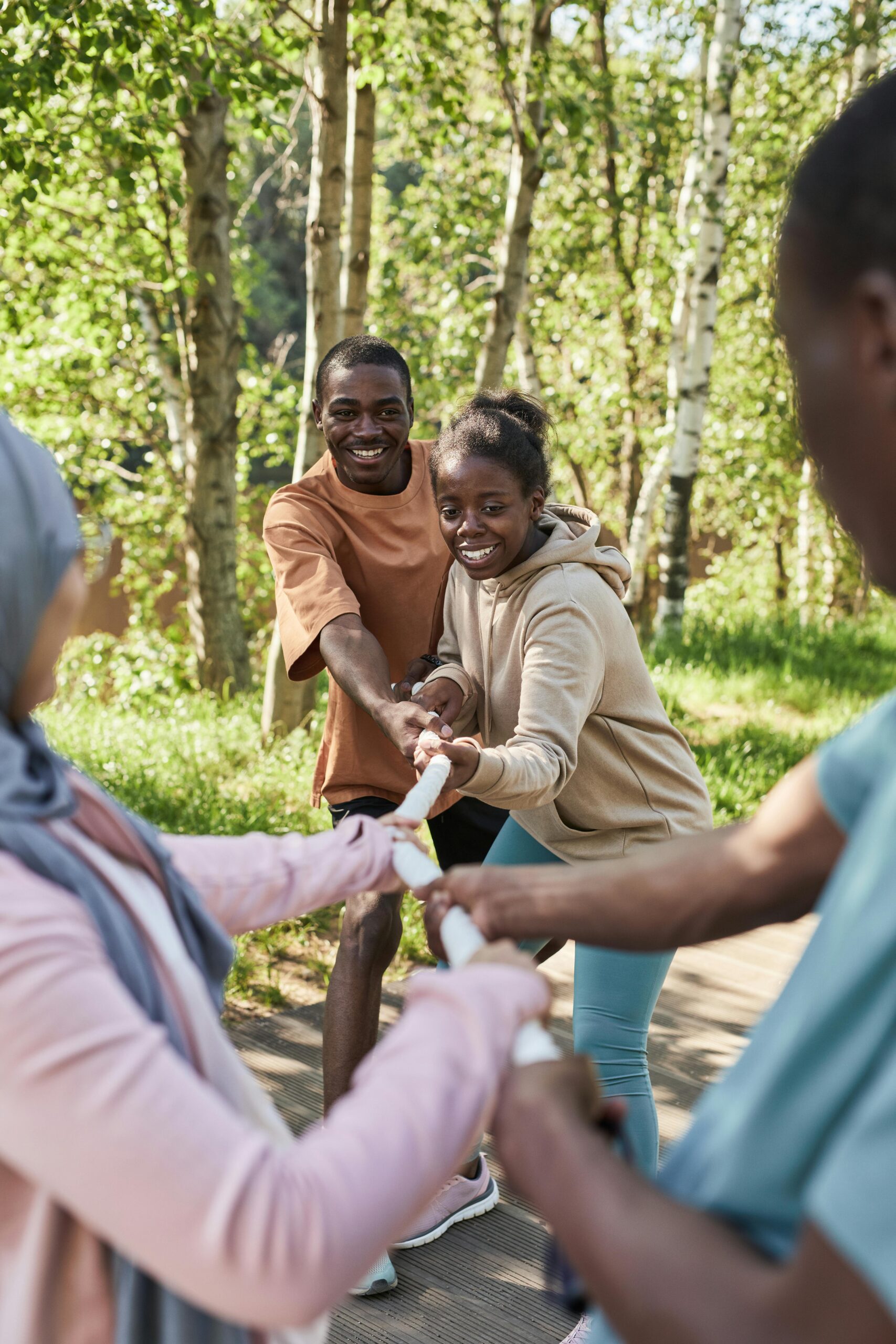 Group of diverse adults enjoying a fun outdoor tug of war game in a park setting.